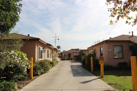 A residential street with houses on both sides and a sign on the right side of the street.