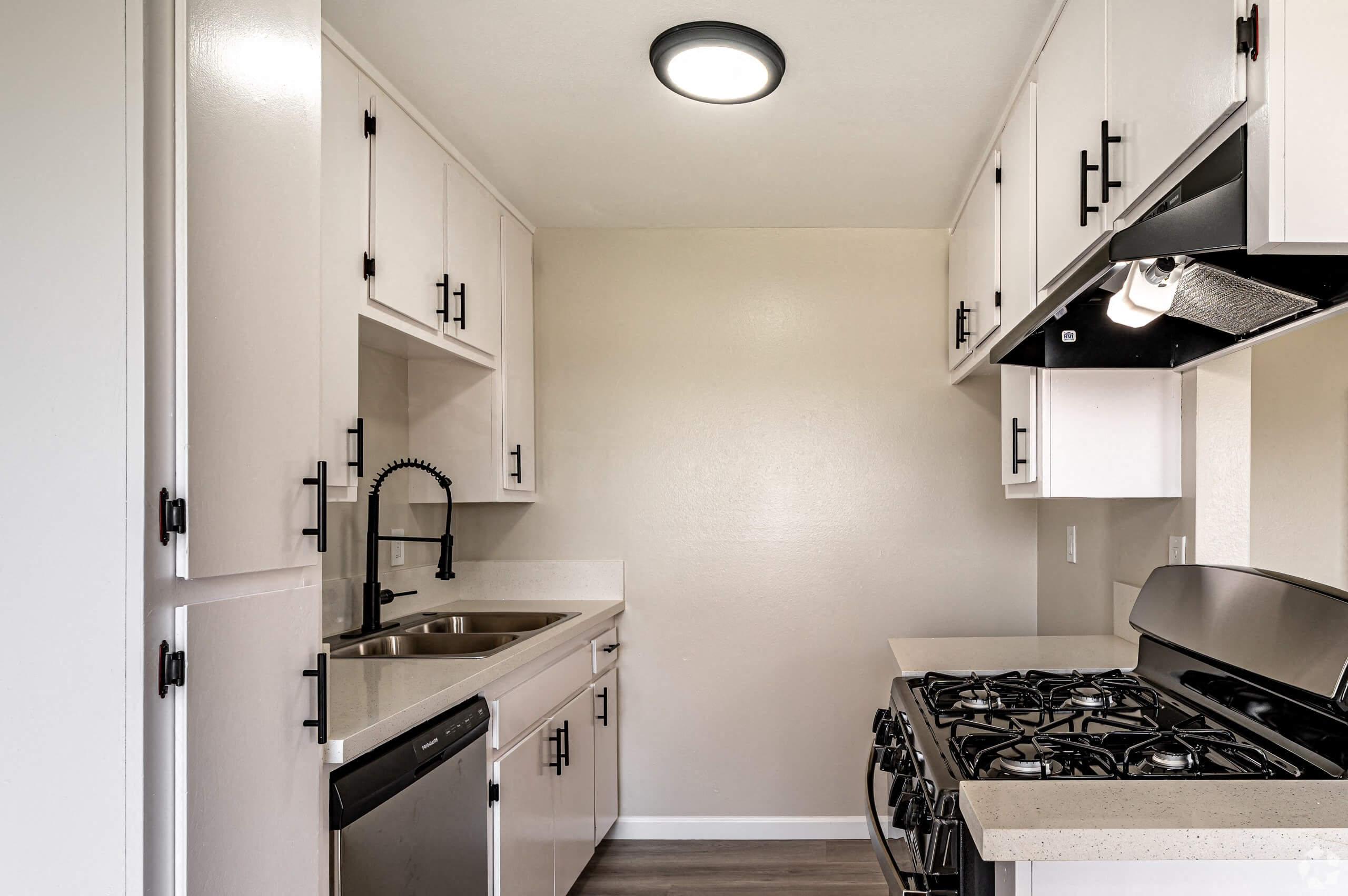 a kitchen with white cabinets and a stove and a sink