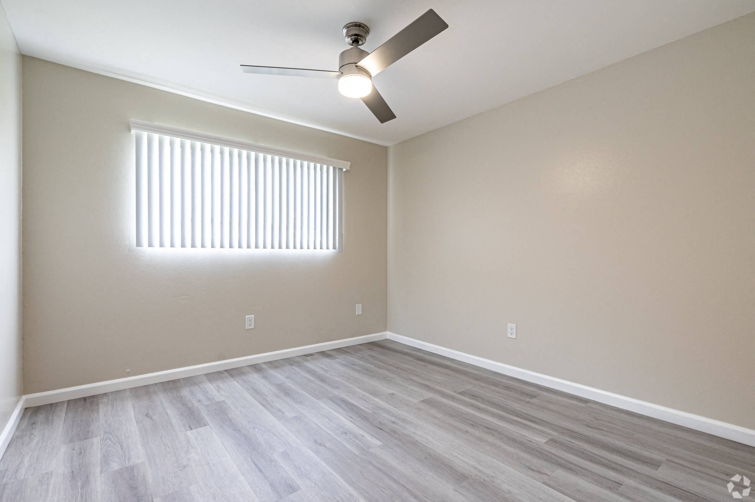 the spacious living room with wood flooring and a ceiling fan