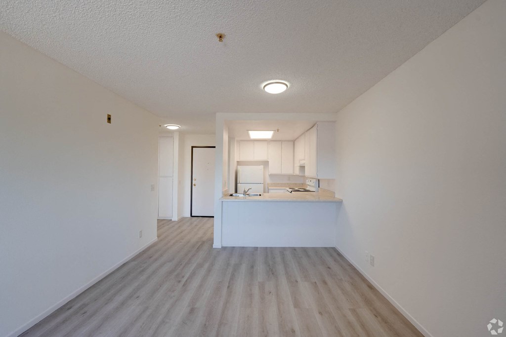 an empty living room and kitchen with white walls and wood floors an empty living room and kitchen with white walls and wood floors at Flamingo Garden Senior Apts, El Monte
