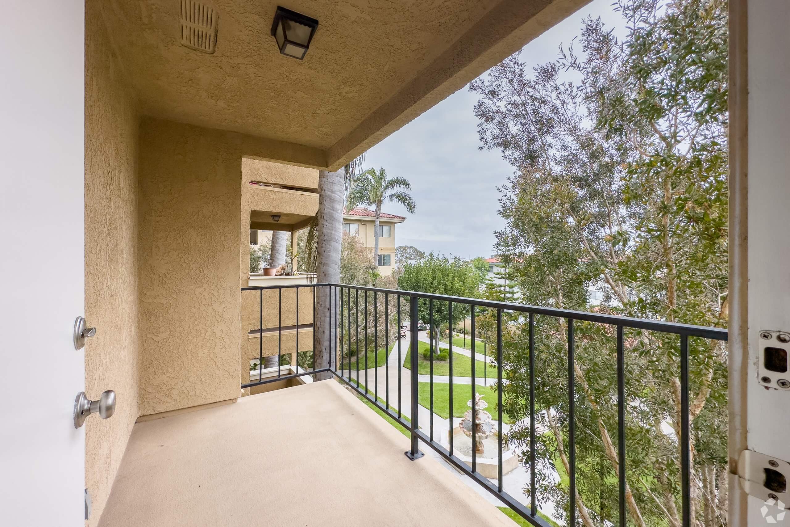 the balcony has a view of the backyard and the trees at Huntington Terrace North Senior, California