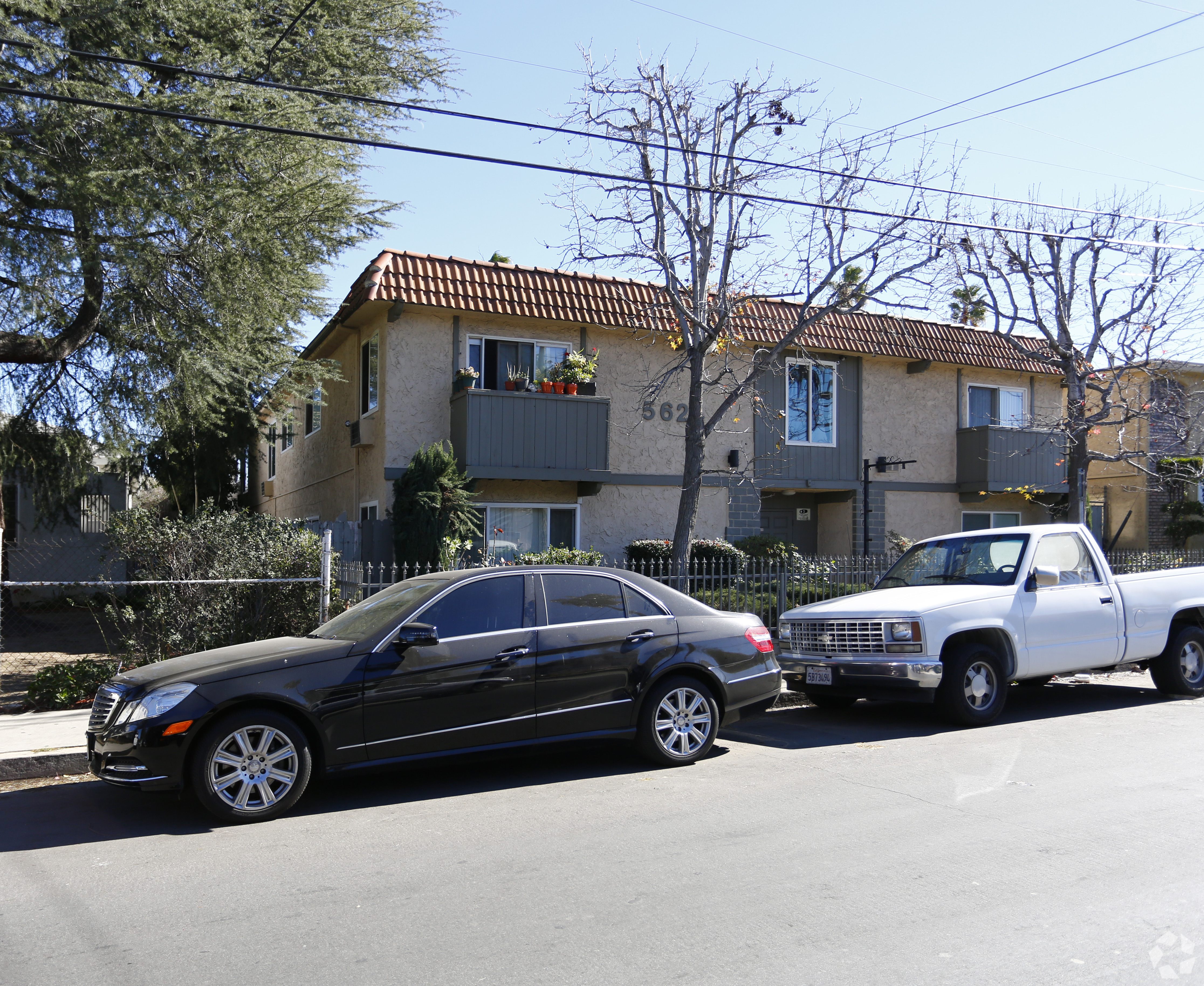 A black car is parked on the street in front of a house.