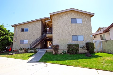 A tan stucco house with a black metal staircase leading to the front door.