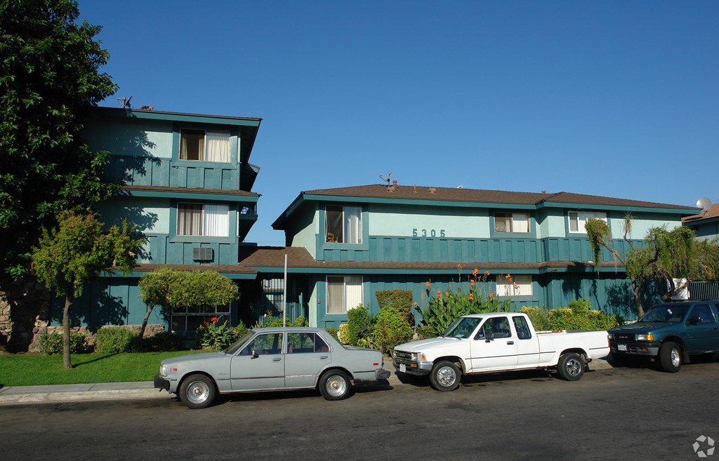 A white truck is parked in front of a blue building.