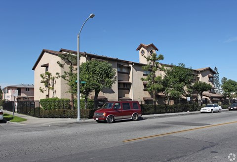 A red van is parked on the side of a street in front of a building.