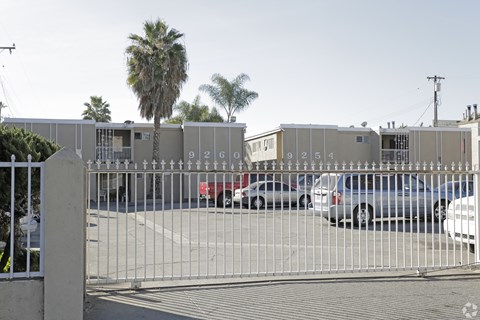 A gate with the numbers 92609254 on it blocks the view of a parking lot.