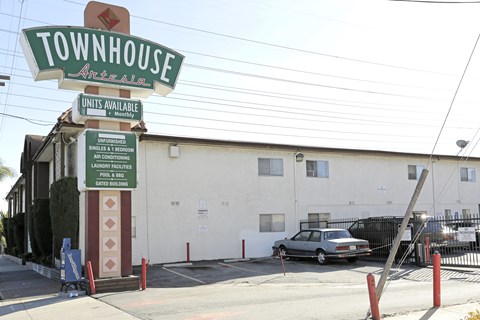 A sign for Townhouse Antelain with a car parked in front.