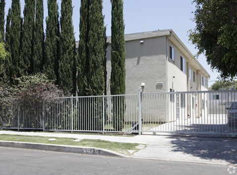 A house is surrounded by a tall fence and tall trees.