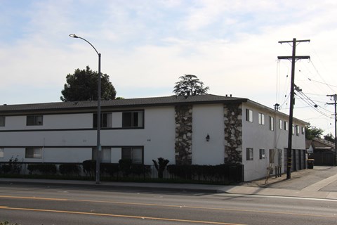 A white building with a black roof and a stone pillar on the side.