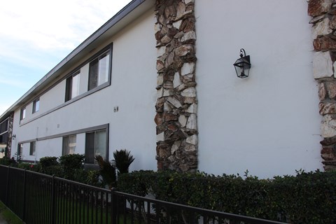 A white house with a stone pillar and a black fence.