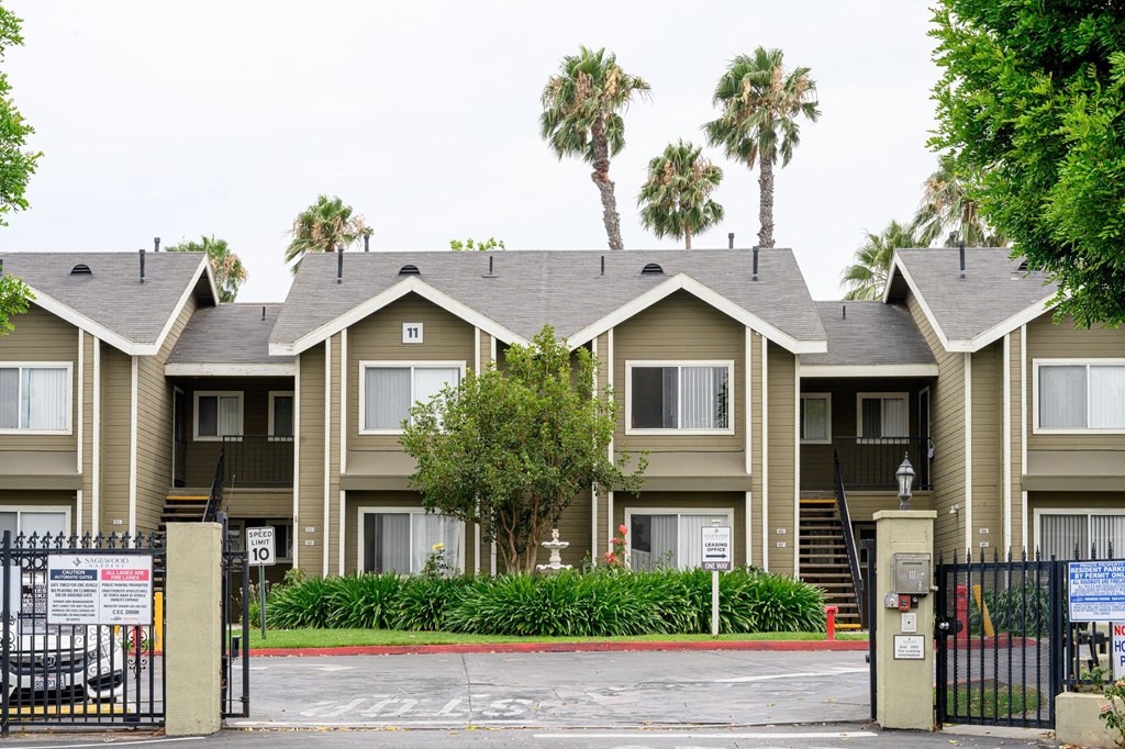a row of apartment buildings with palm trees in the background at Sagewood Gardens Senior Apartments, California, 91745