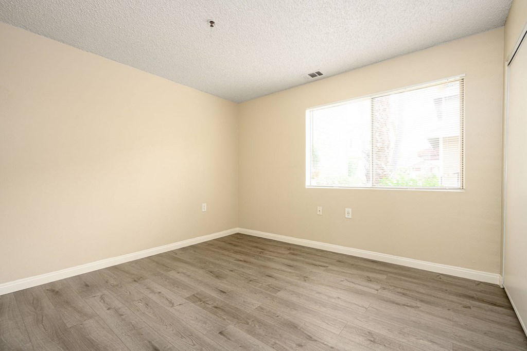 a bedroom with hardwood floors and a large window at Sagewood Gardens Senior Apartments, California