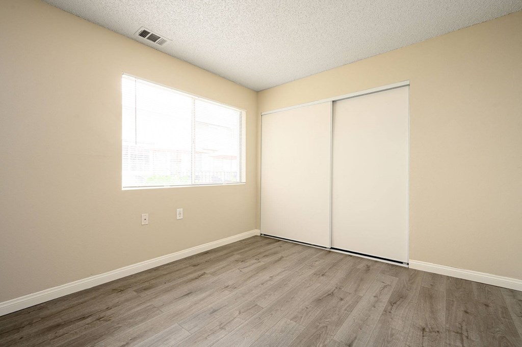 a bedroom with two closets and a window at Sagewood Gardens Senior Apartments, California