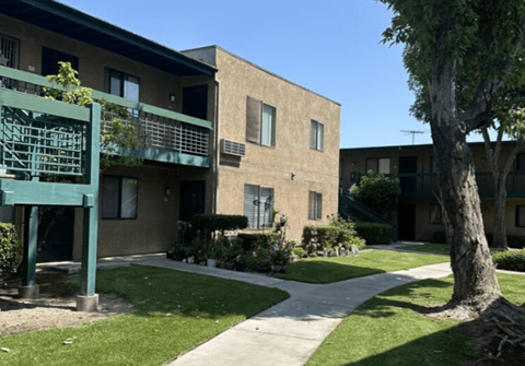A building with a green railing and a tree in front.
