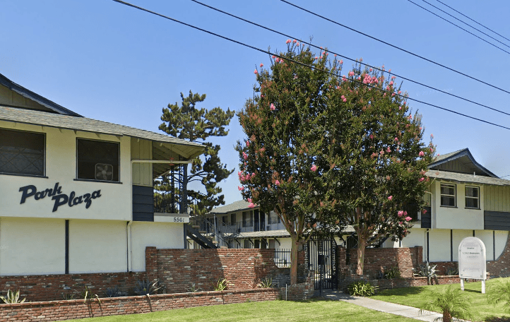 A tree with pink flowers is in front of a building with a sign that says "Park Plaza.".