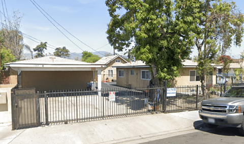 A house with a black gate and a silver truck parked in front.