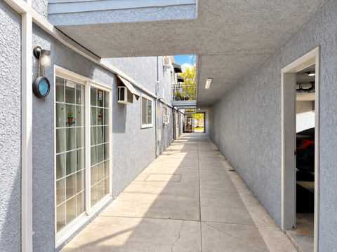 A long, narrow hallway with a white wall on one side and a grey wall on the other.
