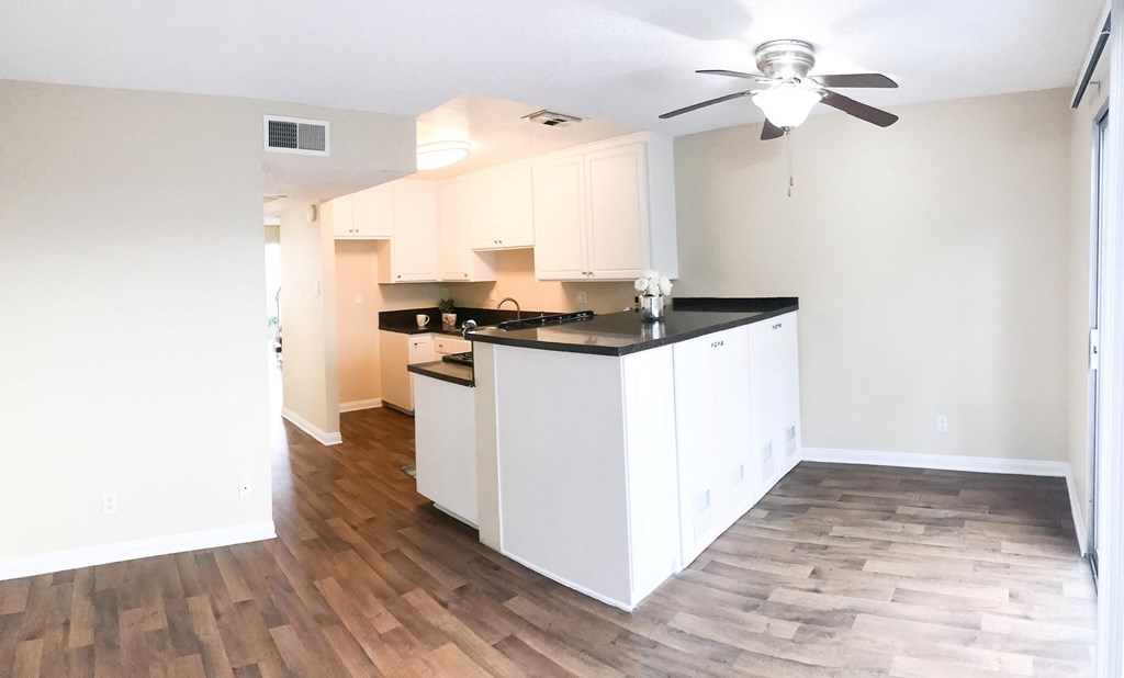 an empty kitchen with white cabinets and a ceiling fan at Terramonte Apartment Homes, Pomona, California