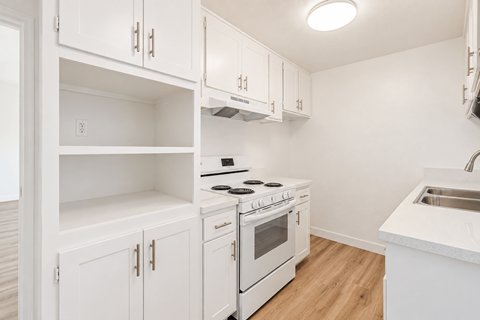 A white kitchen with a stove and sink.