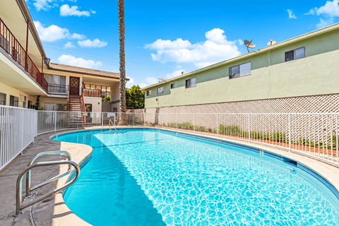 A swimming pool surrounded by a fence and a building in the background.