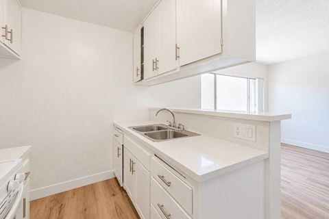 A white kitchen with wooden floors and white cabinets.