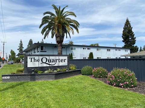 A building with a sign that says "The Quarter" in front of it.