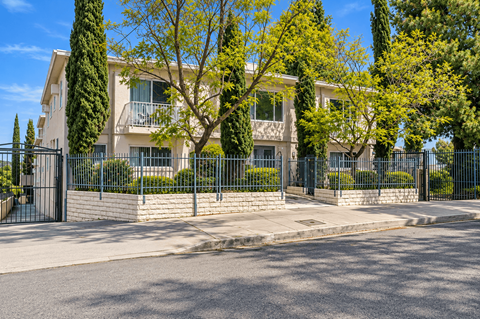 A large house with a black fence and trees in front.
