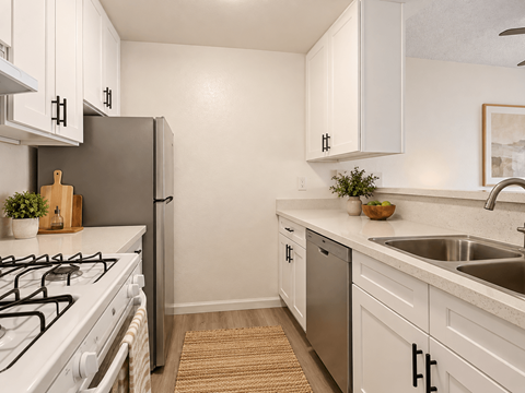 A kitchen with white cabinets and a black fridge.