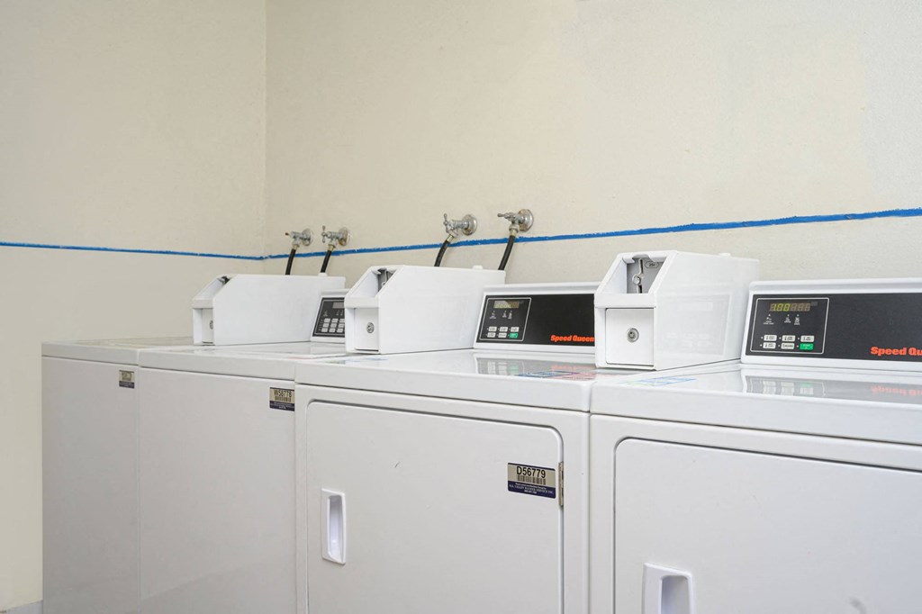 a row of washers and dryers in a laundry room at Villa Hemet, Hemet, CA