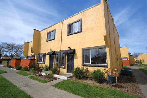 A yellow house with a black door and windows.