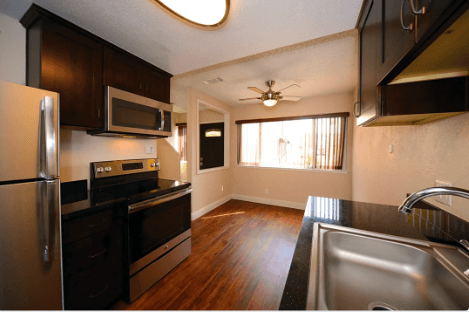 A kitchen with a refrigerator, sink, and stove.