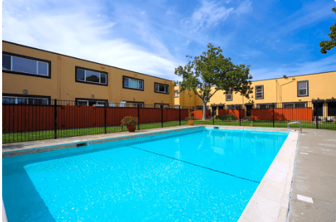 A large swimming pool in front of a yellow building.