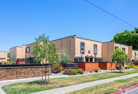A building with a brown and beige exterior and a green lawn in front.