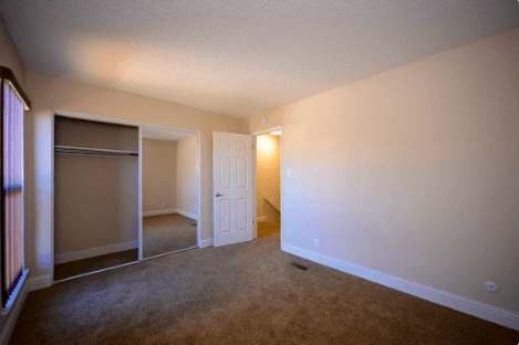 A room with a carpeted floor and a white door.