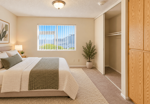 A bedroom with a large bed and a window with blinds.