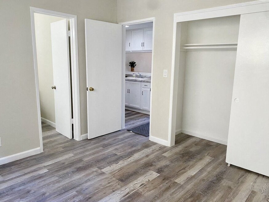a bedroom with white walls and a hardwood floor at South Pointe Apts, Covina, CA 91722