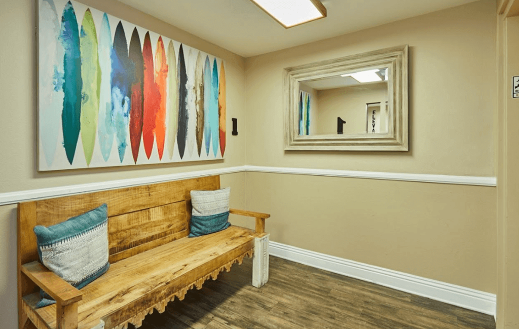 a bench and a painting in a room with a mirror at Huntington Terrace North Senior, Huntington Beach, CA 92648
