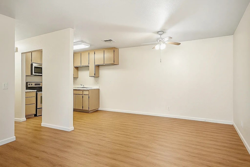 A room with a ceiling fan and wooden flooring.