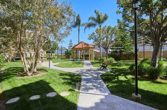a pathway through a park with a gazebo and trees at Huntington Terrace North Senior, California