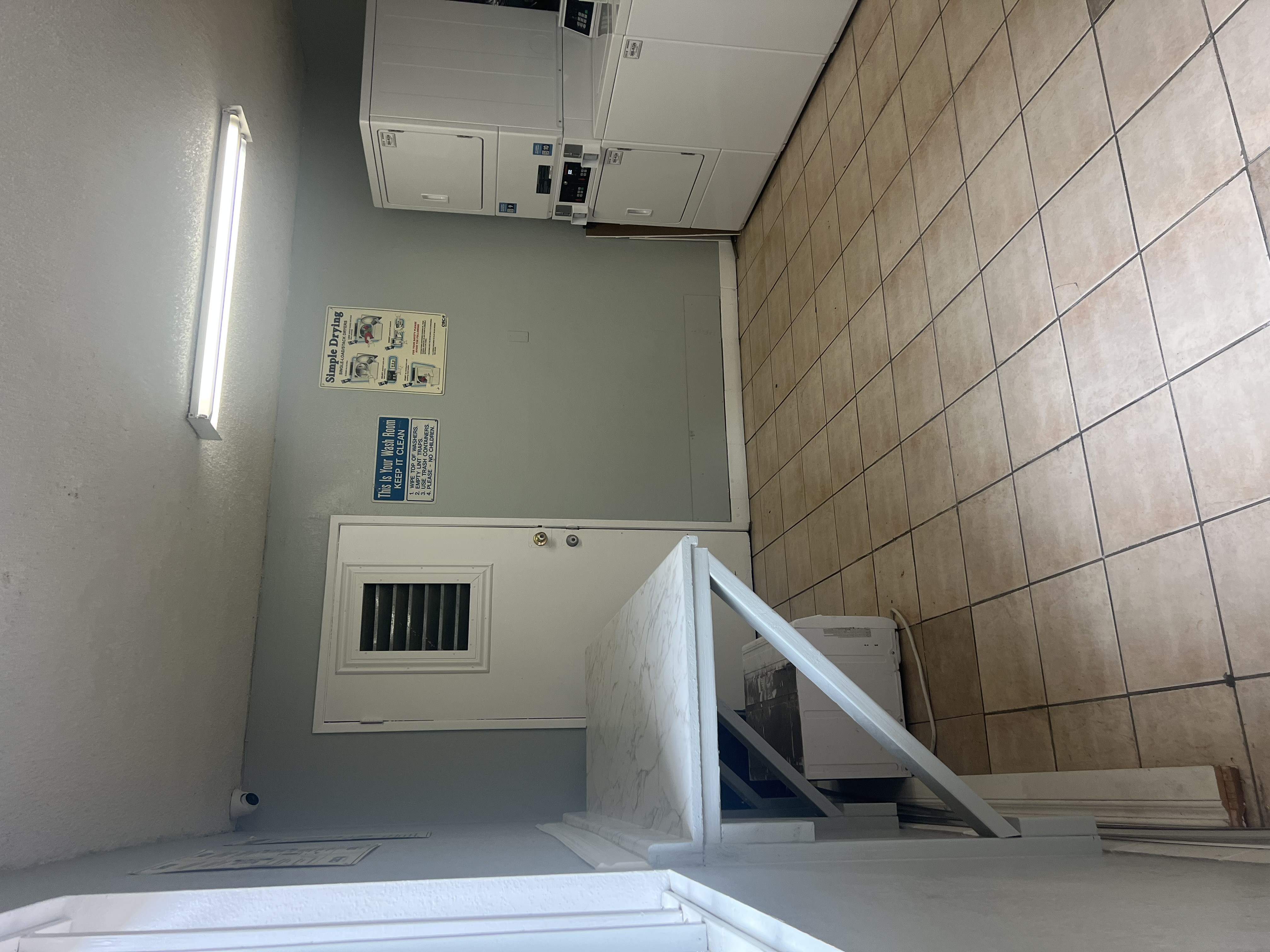 A room with a white wall and a white ceiling with a ventilation system.