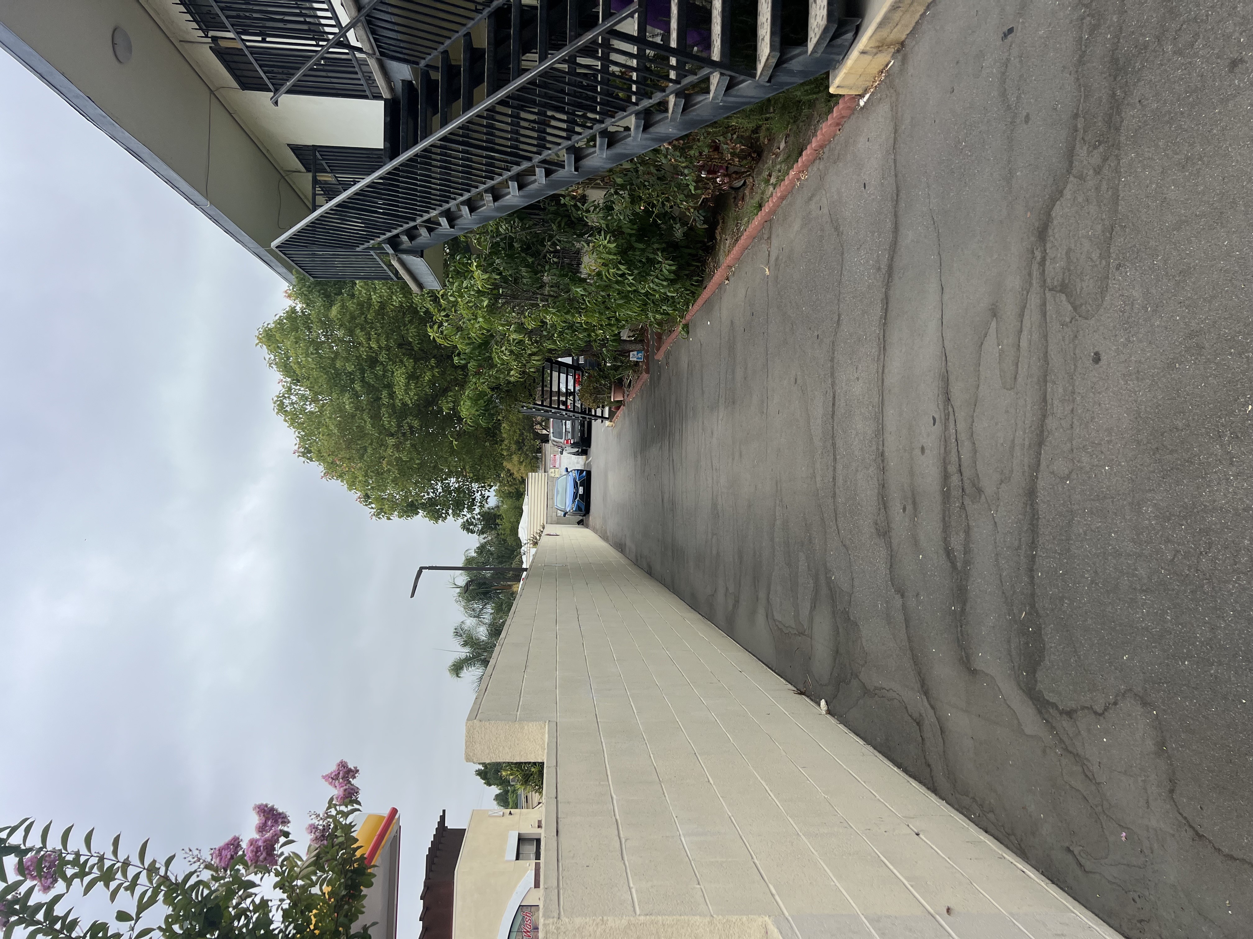 A concrete staircase with a metal railing on the left side and a wall on the right side.