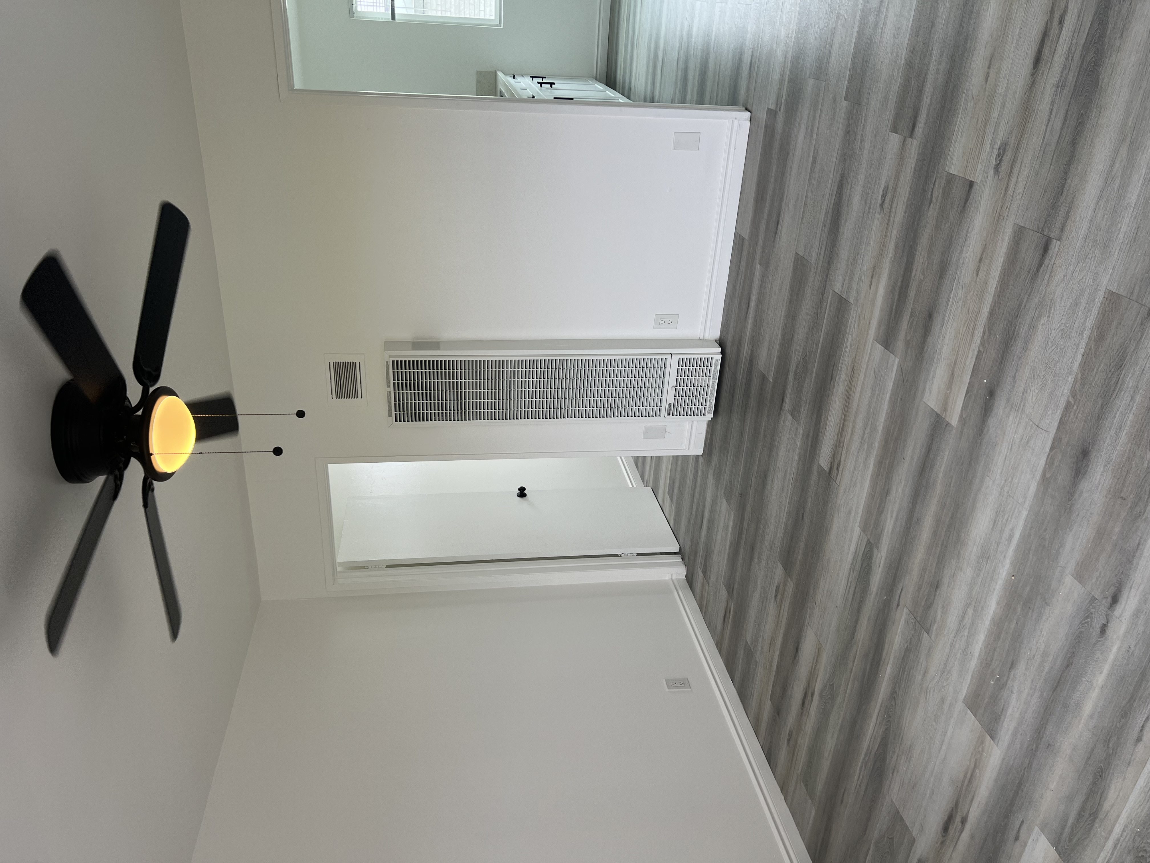 A white air conditioner unit is mounted on a wall with a fan on the left side.