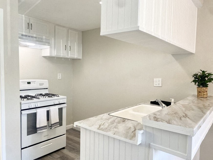 a kitchen with white cabinets and a white stove top oven at South Pointe Apts, Covina, CA