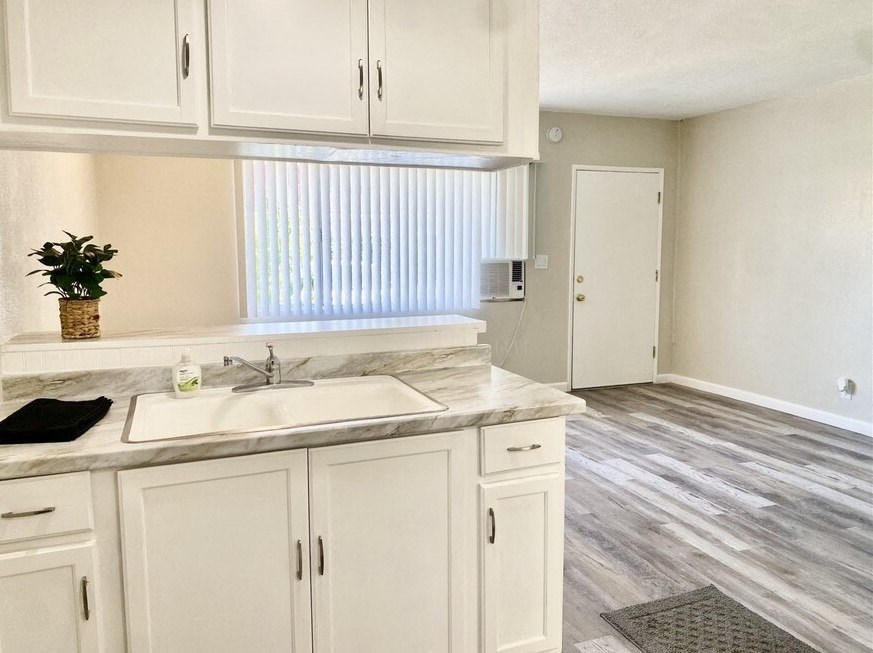a kitchen with white cabinets and a white sink at South Pointe Apts, Covina