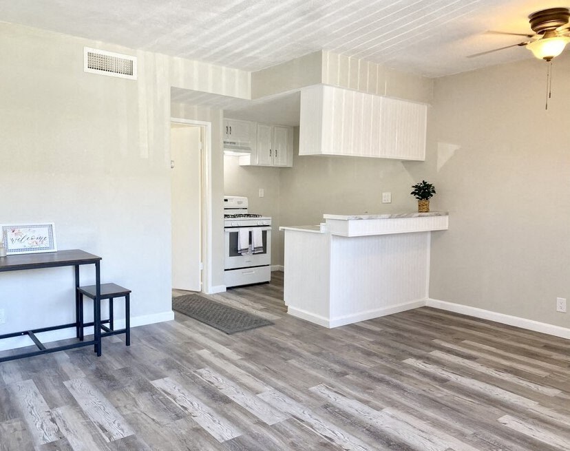 an empty living room with a kitchen in the background a living room with a kitchen and a table