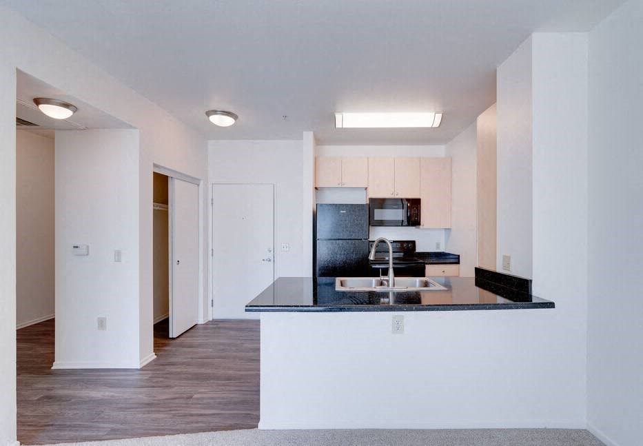 a kitchen with a black counter top and a sink at Helix at University Village, Pomona