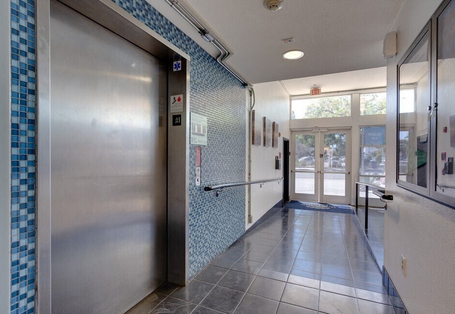 a metal door at the end of a hallway with a blue tile wall at Helix at University Village, Pomona California