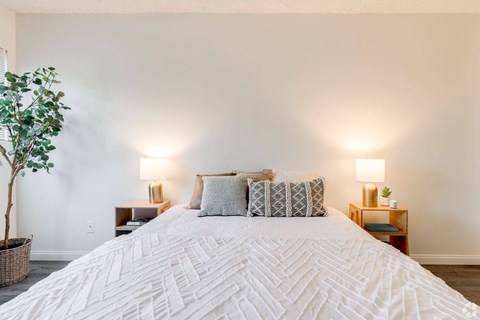 a bedroom with a large white bed and white walls a bedroom with a large white bed and white walls at University Park, Azusa