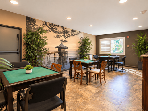 A dining room with a table surrounded by chairs and a mural on the wall.
