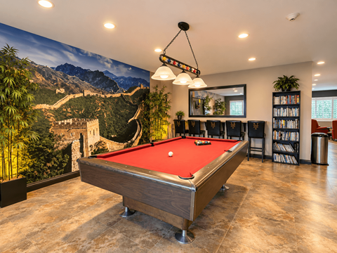A pool table in a room with a large wall mural of the Great Wall of China.